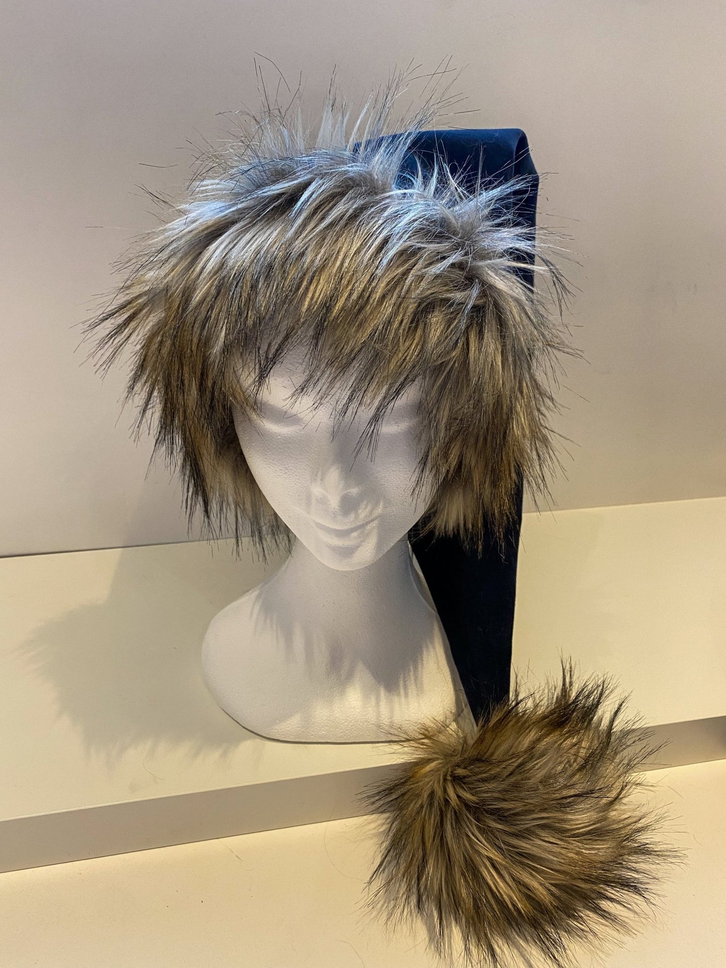 Blå nissehue til voksne. Nissehuen er 40cm lang og er lavet ud af mørkeblå velour og imiteret ulvepels. Nissehuen har en stor bred pelskant og en stor og vamset kvast.