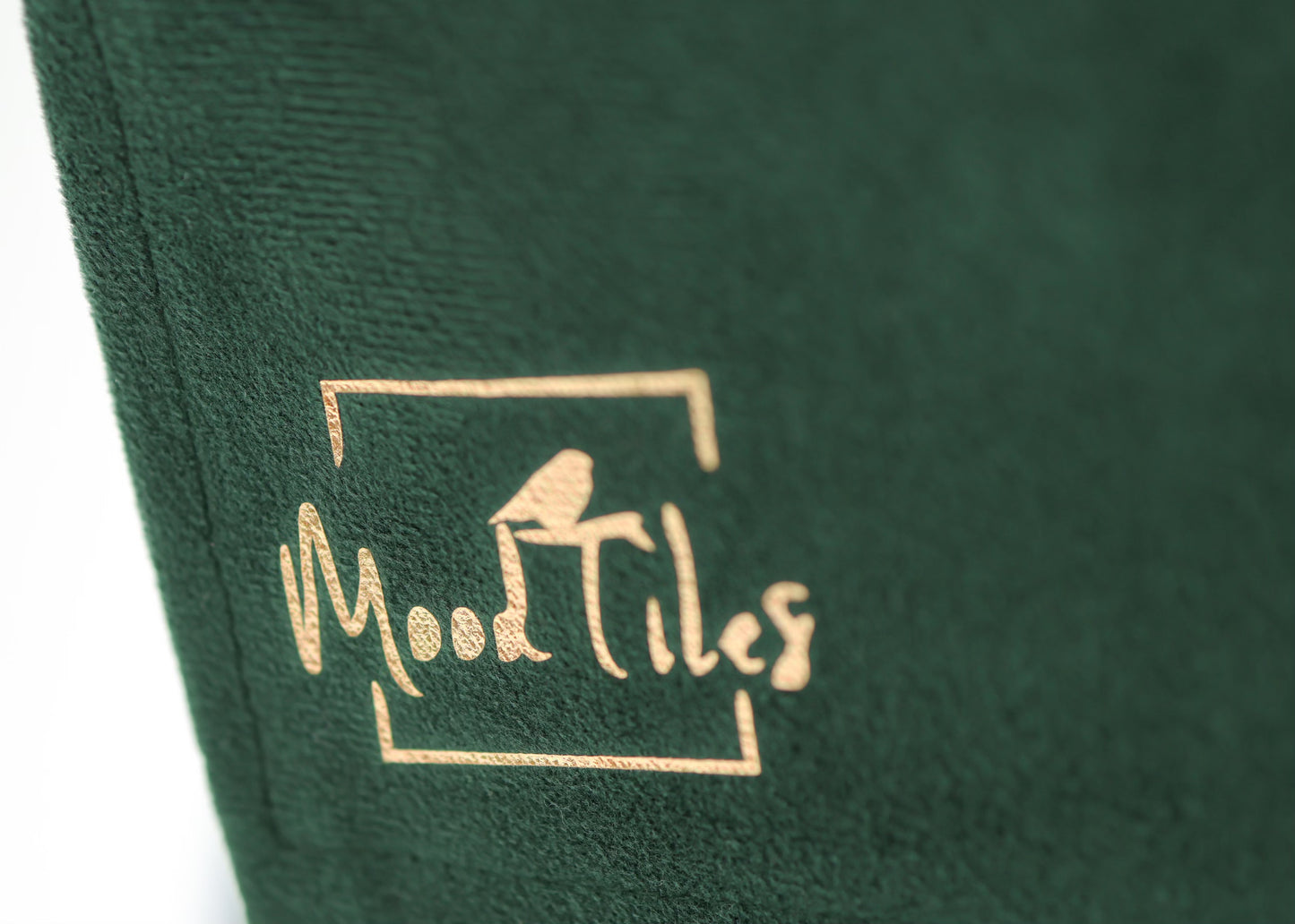 Grøn forklæde zoomet ind på MoodTiles logo i guld