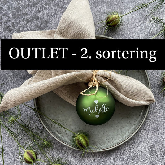 OUTLET julekugle. Mosgrøn julekugle på tallerken. Julekuglen er med navn og små hjerter. Julekugle er brugt som bordkort.